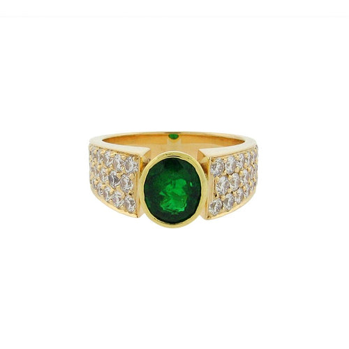 Large oval emerald with pave diamonds set in a 14 k yellow gold ring